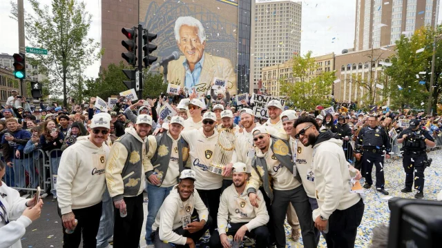 The Brewers stopped the buses along the parade route to take a picture with the Commissioner's Trophy in front of a mural honoring late broadcaster and player Bob Uecker.