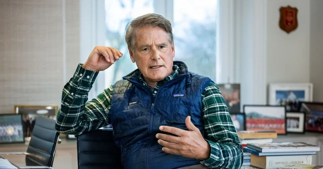 Christer Gardell sitter i ett kontor med böcker och fotografier på skrivbordet.