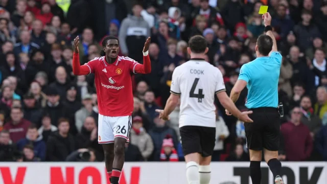 Manchester United's Ayden Heaven is shown a yellow card for a challenge on Bournemouth's Evanilson